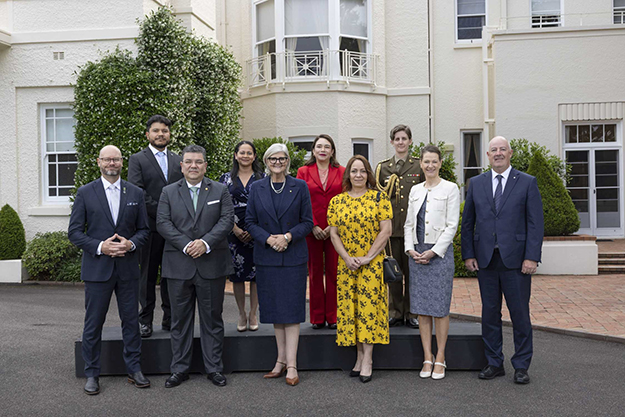 Ten people standing together in two rows outside Australia's Government House.