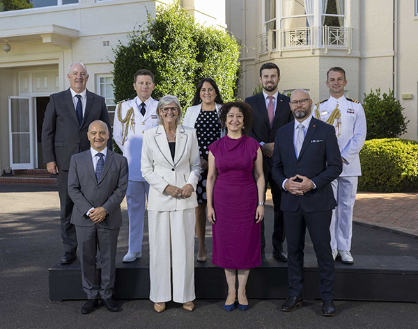 9 people it two rows standing outside Government House in Canberra.