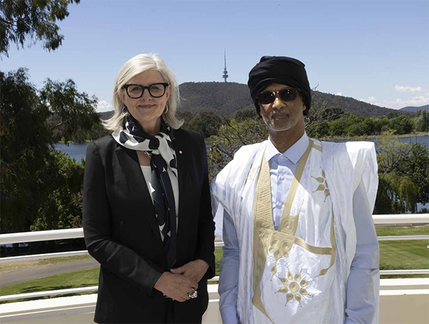 Governor-General of Australia, Sam Mostyn, and His Excellency Dr Mohamed Yahya Teiss, Ambassador of Mauritania in traditional Mauritanian clothing, standing outside with Canberra's Black Mountain in the background.