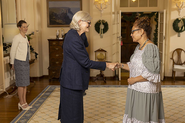 Two women standing inside, shaking hands