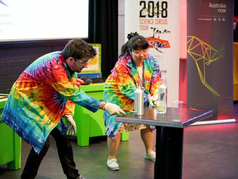 Science communicators wearing colourful jackets and conducting an experiement