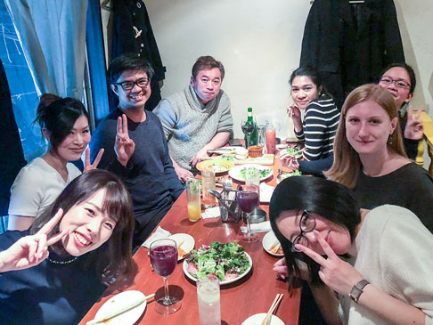 Eight people sharing a meal at a dinner table.