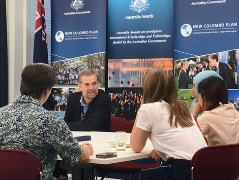 Attendees sitting at table in front of Australia Awards and New Colombo Plan banners