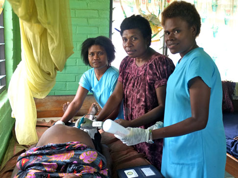 Three women in a clinic, tending to a patient.