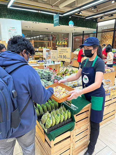 Female worker handing out samples to a customer in a grocery store.