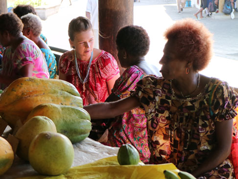 Stephanie at a market, talking with market sellers.