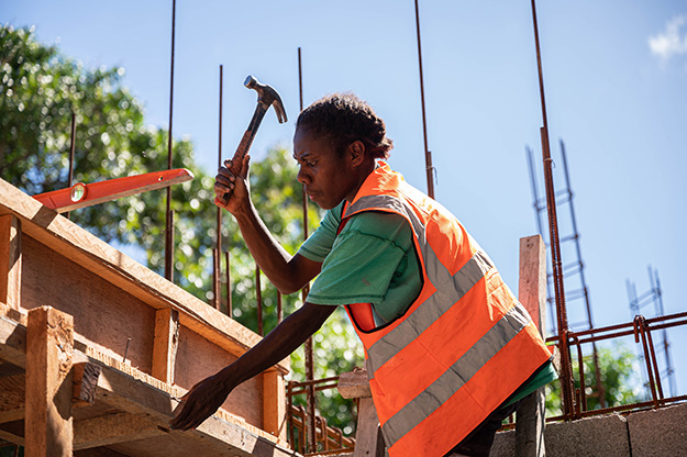 Vanuatu construction worker with hammer in hand on a building site.