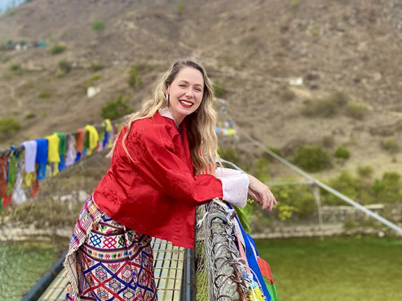 Samantha standing on a footbridge adorned with colourful Buddhist flags