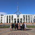 Nine women standing together in front of Parliament House in Canberra, Australia. 