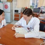 Two women seated at a desk, one woman taking notes while another speaks.