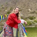 Samantha standing on a footbridge adorned with colourful Buddhist flags