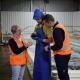 The CEO and a colleague in hi viz vests and a worker in protective fisheries apron and gloves, examine a sea urchin for quality.