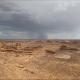 A desert landscape with a storm off in the far distance