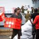 Residents of Tanna Island, alongside ship’s company from HMAS Canberra, unload Australian Aid humanitarian assistance. The red boxes being unloaded are Kitchen Kits. Kitchen Kits provide essential supplies – such as buckets and cooking pots and utensils – to support a household to cook basic meals and store drinking water. 