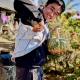 Photo of Andy Tran in a garden holding a fruit and vegetable. 