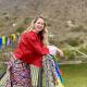 Samantha standing on a footbridge adorned with colourful Buddhist flags