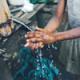 Photo of young girl washing her hands using a bamboo tap.