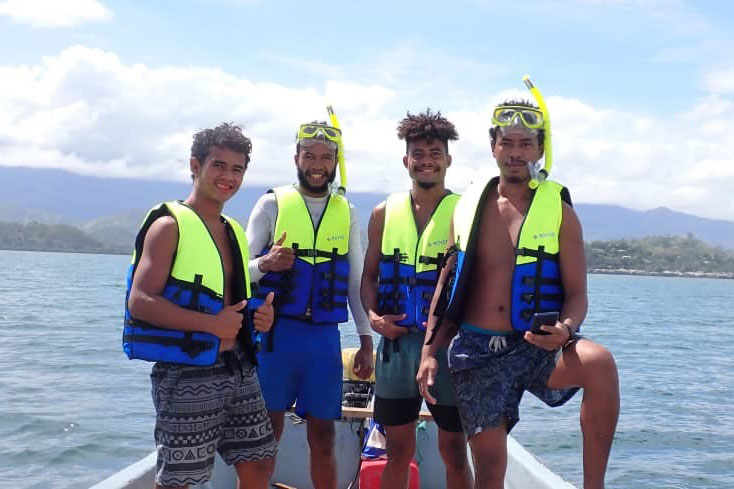 Group photo of 4 PNG boy in a tinnie boat off the coast.