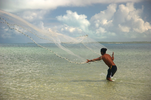 Man casting a net in knee high waters