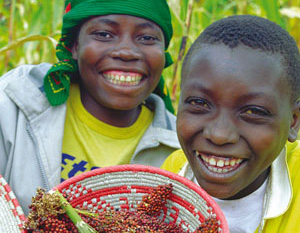 Two young smiling boys holding a basket of berries.