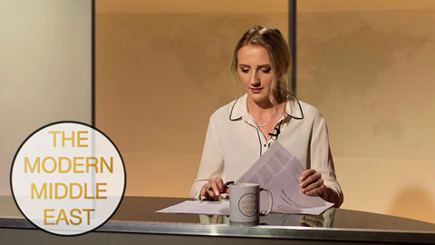 Female presenter preparing her notes on desk with a logo in the corner of the picture that says 'The Mordern Middle East.