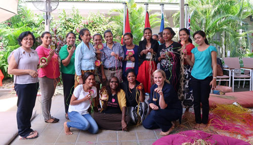 Women posing for photo with their woven products.