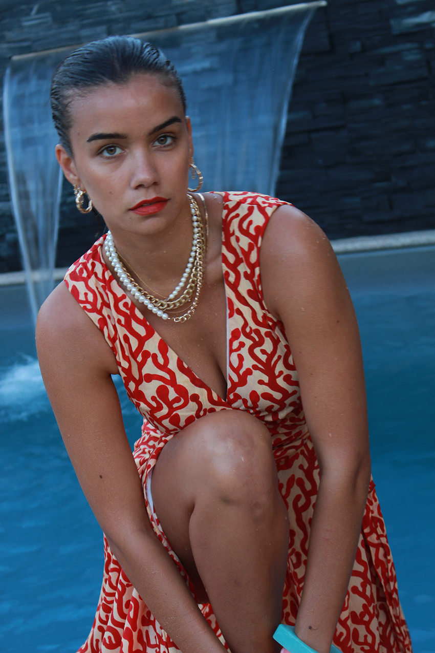 model wearing a red pattern dress, necklaces and hoop earrings