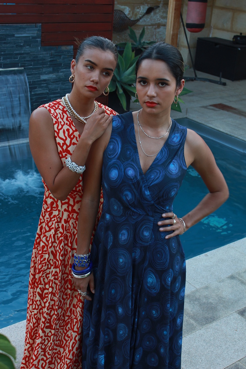 two girl models, one in a red pattern dress standing behind the other in a blue pattern dress