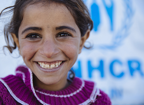 Girl smiling in front of UNHCR sign