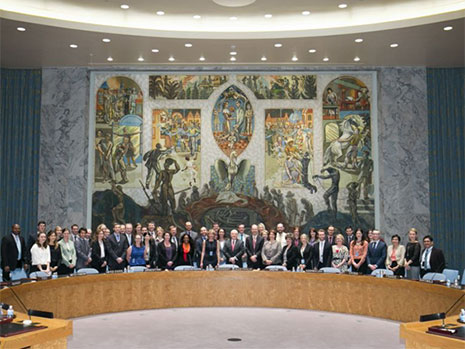 Class photo of Australian staff behind a large curved table in a large room