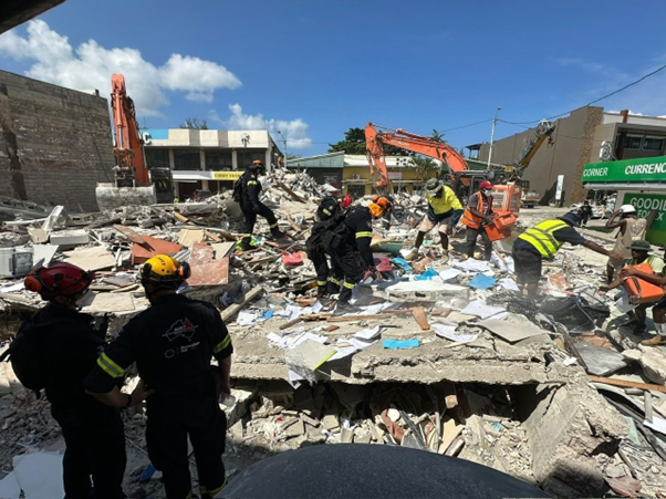 Search and Rescue personnel search through the rubble of a collapsed building.