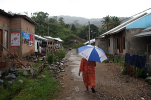 A woman walks through a village which is being rebuilt.